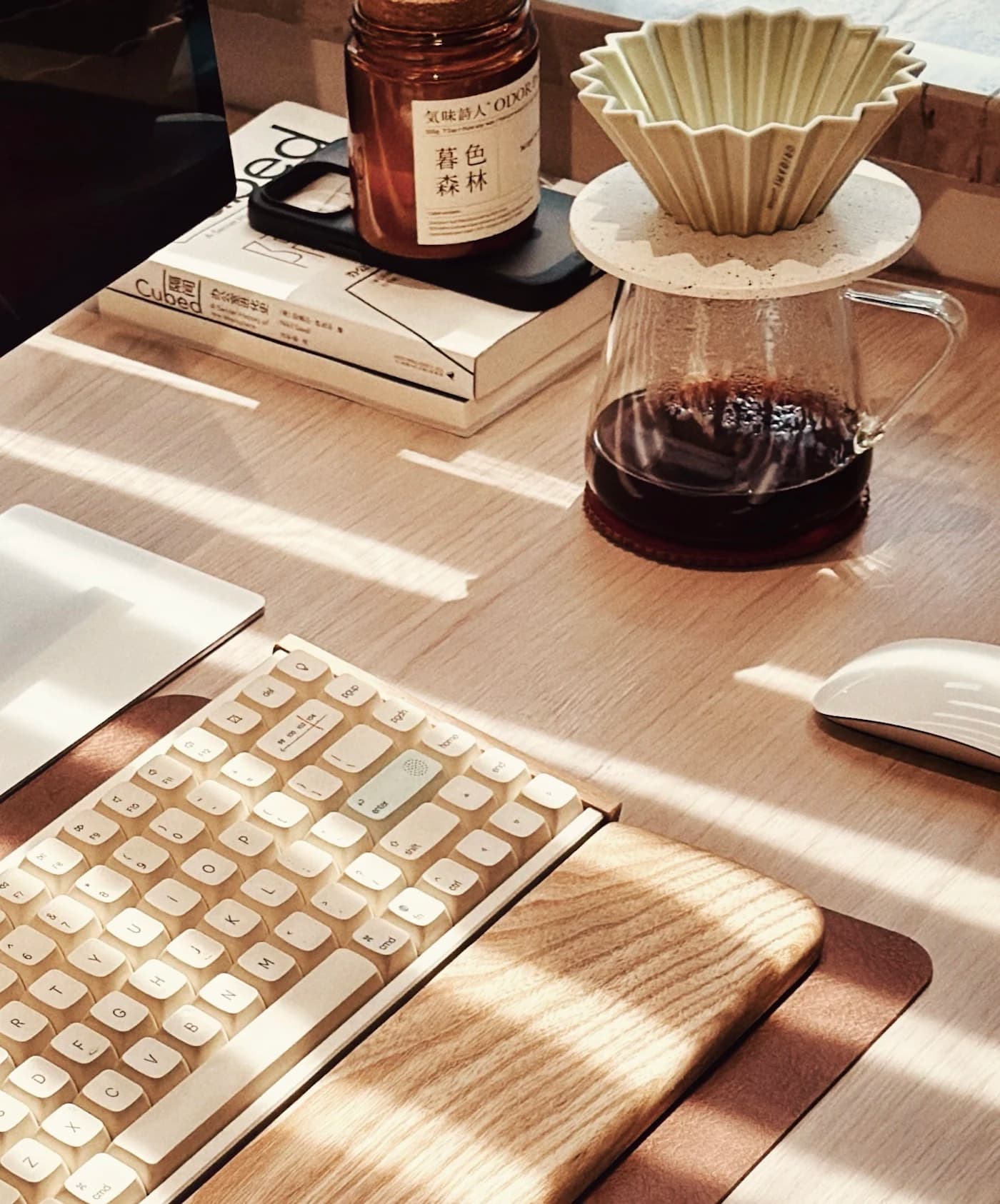 Mesa de trabalho com teclado, livros e café em luz natural